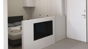Habitación moderna con cama, almacenamiento integrado, televisor de pantalla plana y aire acondicionado.