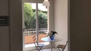 Un salón moderno con una mesa redonda, dos sillones, un sofá y vistas a un balcón con vegetación.