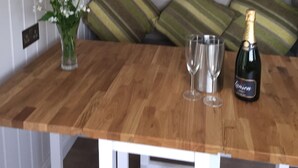 A wooden table with a vase of flowers, two glasses, and a bottle of champagne.