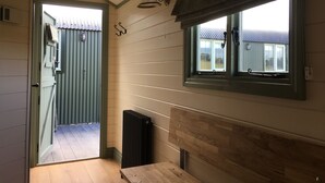 A room with a wooden table, a radiator, a window with curtains, and a door leading to an outdoor area.