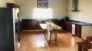 Una cocina con una isla central, armarios de madera oscura, un refrigerador de acero inoxidable y una ventana sobre el fregadero.
