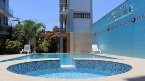 A swimming pool with tiled edges and a clear blue center, surrounded by lounge chairs and a building with a sign reading "Gran Hotel Villa Del Sur". - Gran Hotel Villa del Sur (San Vicente de Cañete)