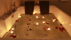 A bathtub with rose petals and candles. - Gran Hotel Villa del Sur (San Vicente de Cañete)