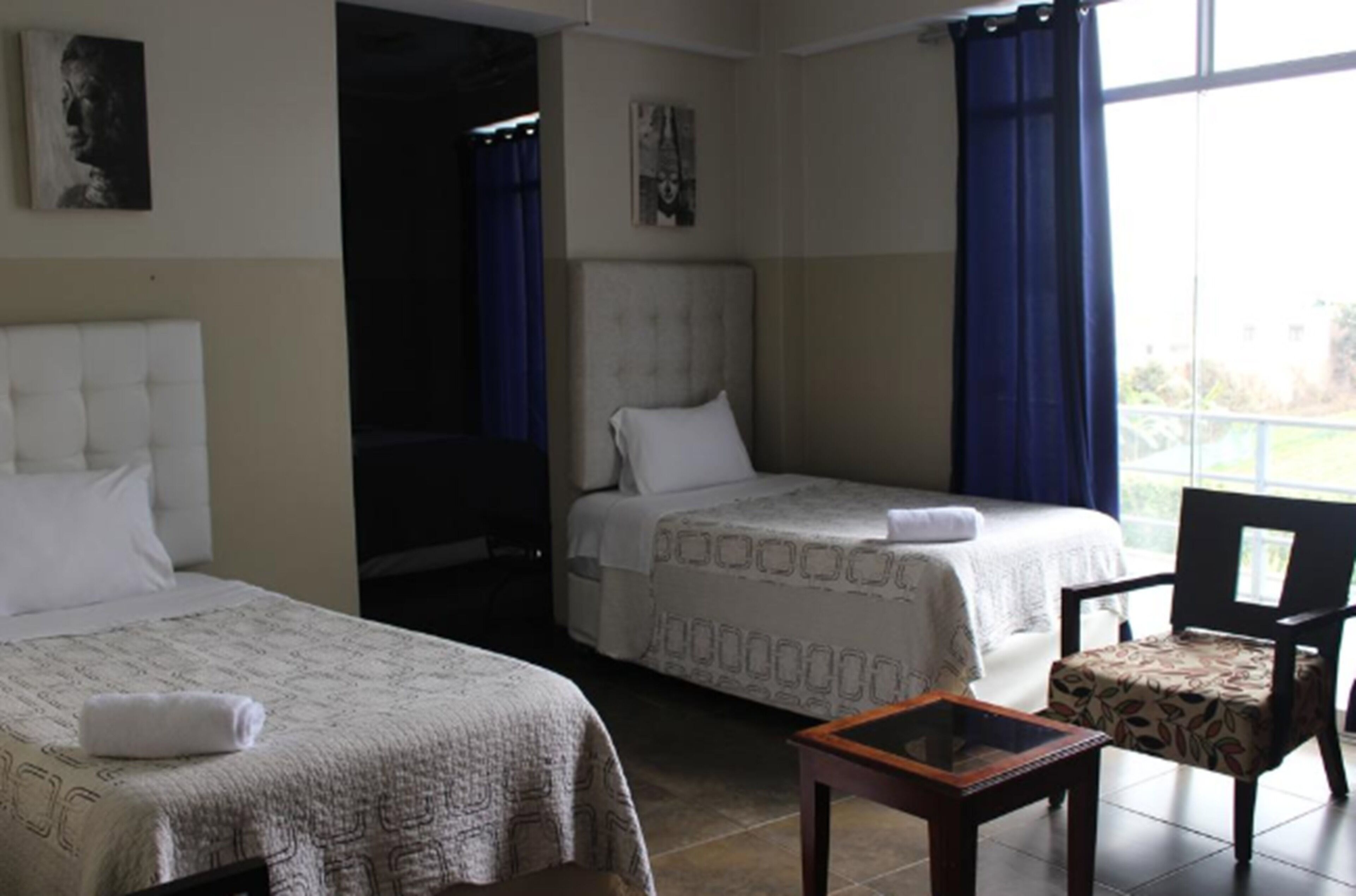 Habitación de hotel con dos camas, una mesita y una silla.