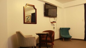 A room with a television mounted on the wall, a small table, and two chairs. - Gran Hotel Villa del Sur (San Vicente de Cañete)
