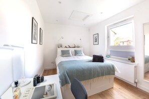 Un dormitorio moderno con cama, escritorio y ventana.