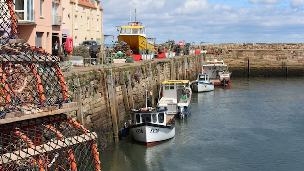 Un puerto con barcos amarrados, un edificio con balcones y una grúa al fondo.