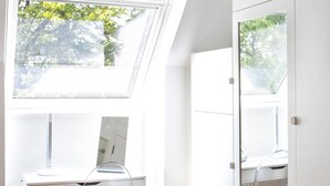 Una habitación moderna y luminosa con tragaluz, muebles blancos y vistas a zonas verdes.