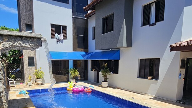 Una casa moderna de dos pisos con piscina, baldosas de piedra y plantas en macetas.