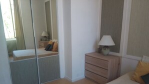 A bedroom with a bed, a nightstand, a lamp, a dresser, and a mirror.