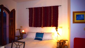 Un dormitorio con cama, mesita de noche, lámpara, silla y puerta.