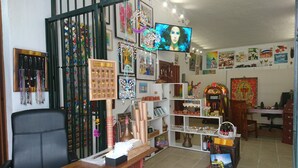 Una habitación con un escritorio de madera, estanterías con diversos objetos, un televisor y obras de arte en las paredes.