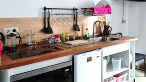 Una cocina compacta con encimera de madera, horno empotrado, lavabo y un refrigerador pequeño.