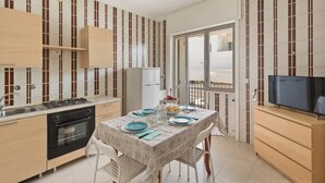 A compact kitchen with a gas stove, oven, and a dining area with a table set for two. - Residence Kalura - Trilo con Balcone (SP) (Porto Cesareo)