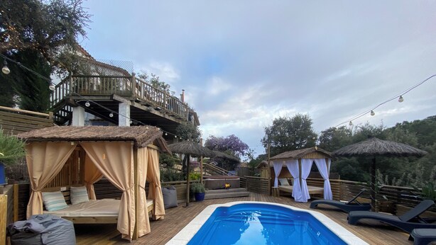 A pool area with a wooden deck, a hot tub, and a covered seating area with a view of the surrounding landscape. - Beautiful studio/apartment with air conditioning and use of pool.  (Begur)