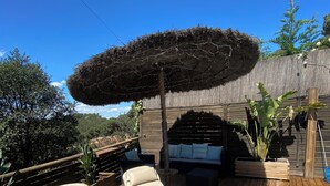 A wooden deck with two lounge chairs, a thatched umbrella, a barbecue grill, and a pool. - Beautiful studio/apartment with air conditioning and use of pool.  (Begur)