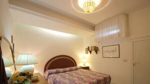 A bedroom with a bed, bedside table, lamp, and wall-mounted light fixture.