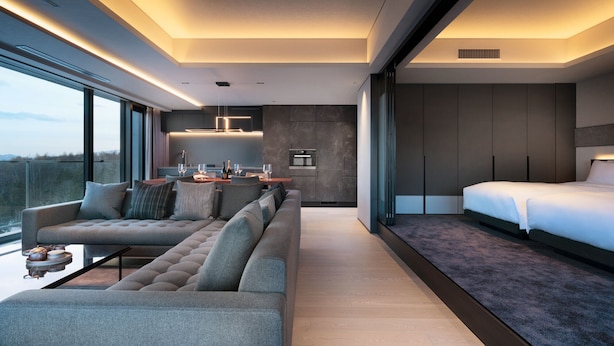 A modern hotel room with a large bed, a sofa, a dining area, and a kitchen. - Sansui Niseko (Kutchan)