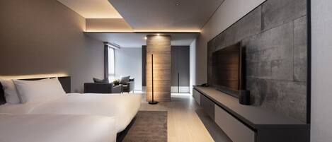 Une chambre d’hôtel moderne dotée d’un grand lit, d’un coin salon, d’un téléviseur fixé au mur et d’un pilier central.