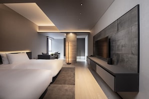 A modern hotel room with a large bed, a seating area, a TV mounted on the wall, and a central pillar. - Sansui Niseko (Kutchan)