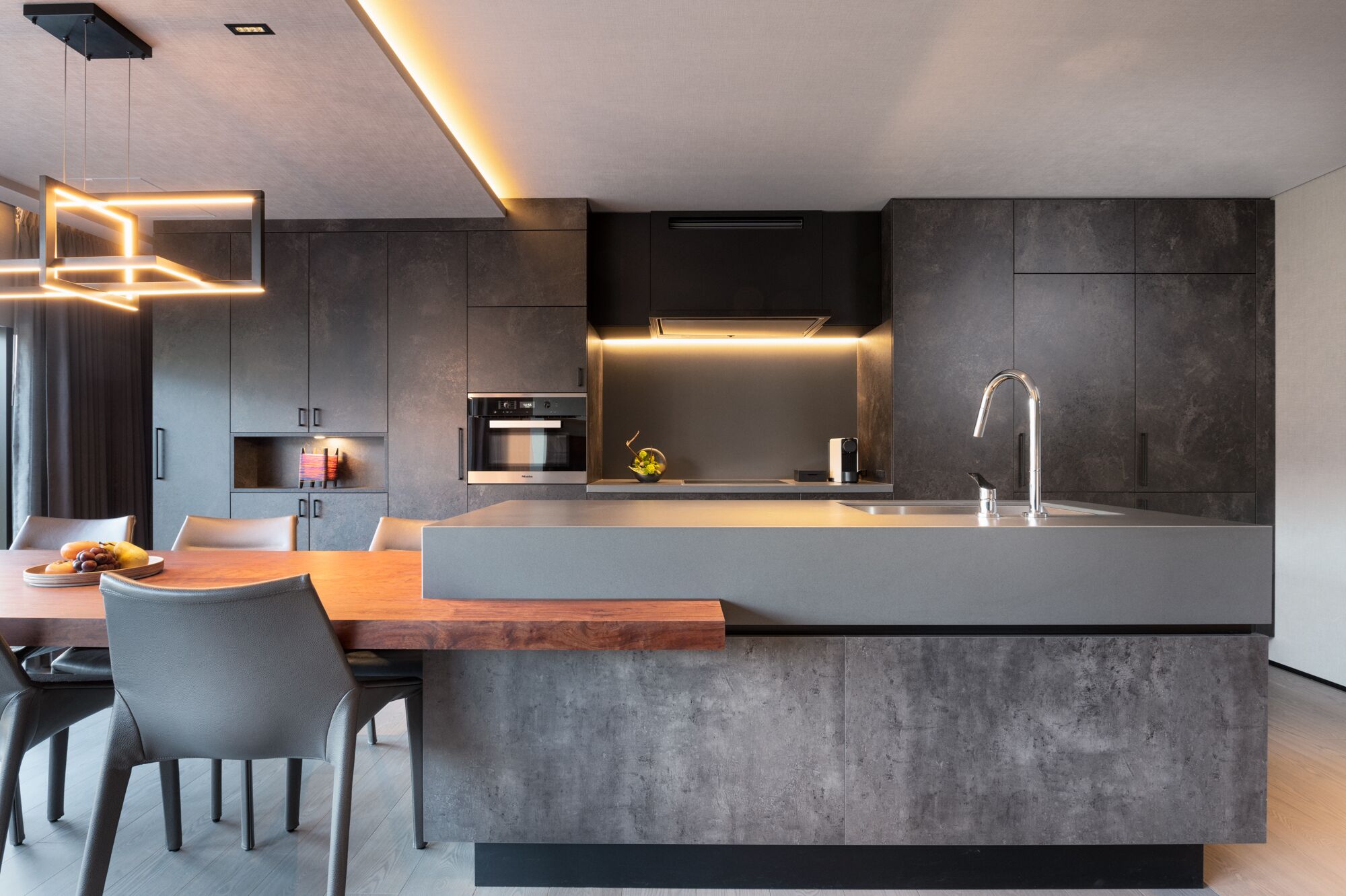 Una cocina moderna con una isla central, horno empotrado y electrodomésticos de acero inoxidable.