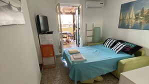 Una habitación pequeña y bien iluminada con una cama, un televisor y un cuadro en la pared.