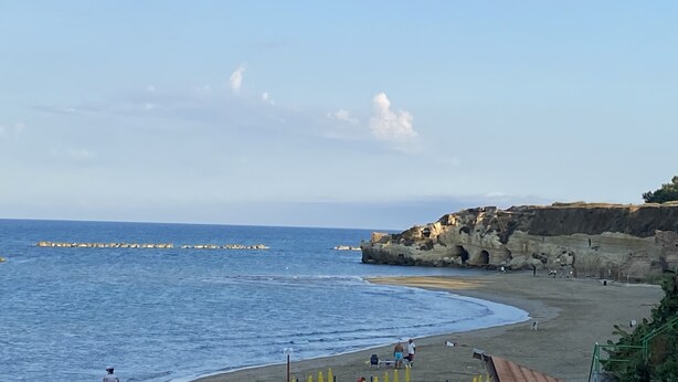 Una playa costera con acantilados rocosos y cielo despejado.