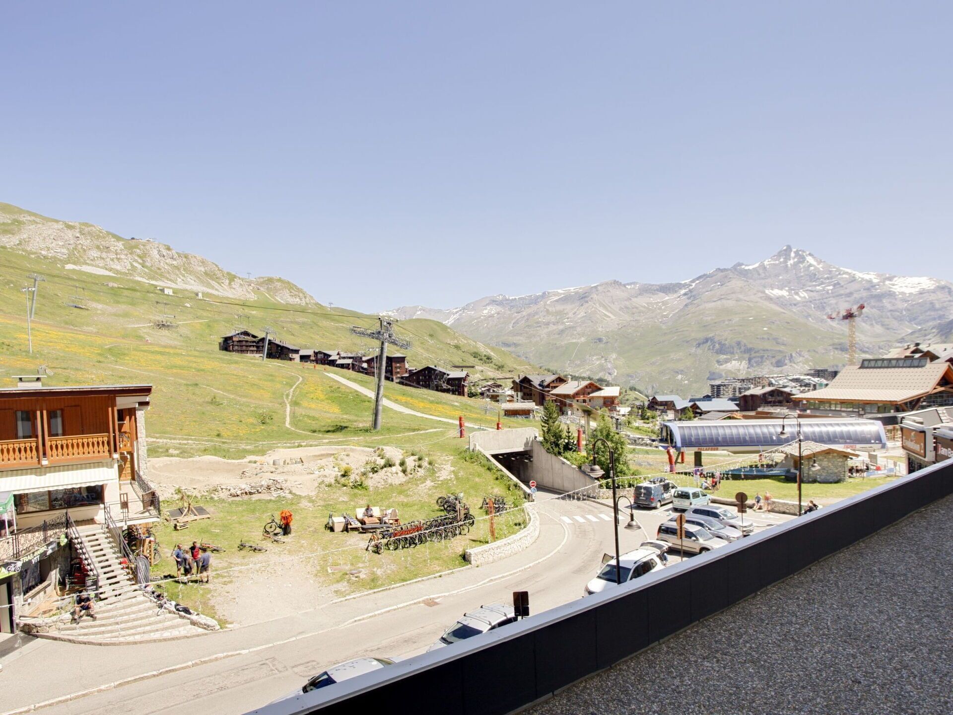 A mountain resort with wooden buildings, a ski lift, and a road leading to a parking area.