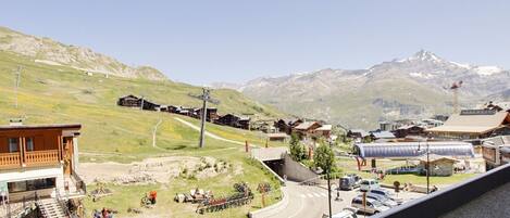 A mountain resort with wooden buildings, a ski lift, and a road leading to a parking area.