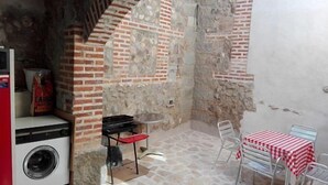 Una cocina pequeña y rústica con lavadora, estufa a gas y una mesa con sillas.