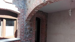 Una habitación con pared de piedra, un arco de ladrillo y una ventana.