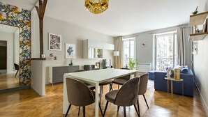 Un salon moderne comprenant un coin repas, un parquet en bois et un grand miroir orné d’un motif floral.