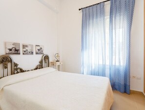 A bedroom with a bed, a nightstand, and a window with blue curtains.