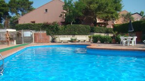 A clear blue swimming pool with a tiled edge, surrounded by a low brick wall. There are white outdoor chairs and a small table in the background. - CASA PARADISO Vacanze  (Costa Saracena - Castelluccio)