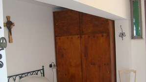 A bedroom with a large bed, wooden wardrobe, and a chair. - CASA PARADISO Vacanze  (Costa Saracena - Castelluccio)