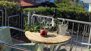 A patio with a round wooden table, two chairs, and a bottle of wine. - CASA PARADISO Vacanze  (Costa Saracena - Castelluccio)