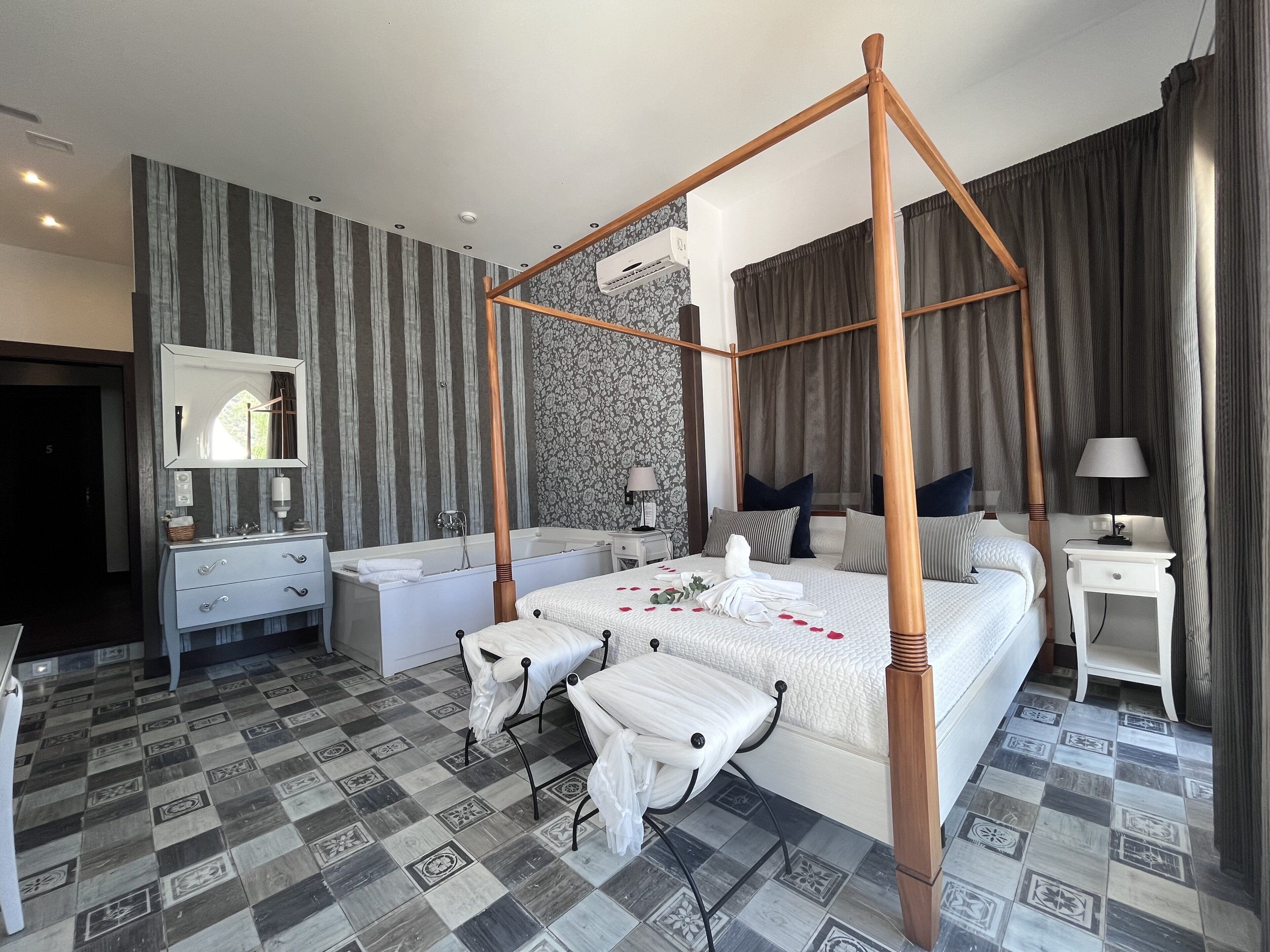 Una cama con dosel, una mesita de noche con una lámpara, un tocador con espejo y un baño con bañera.