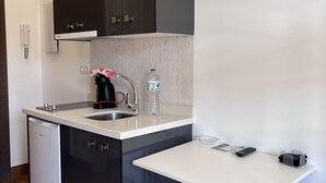 A compact kitchen with dark cabinets, a white countertop, a sink, a coffee maker, a water bottle, and a small stool. - Suite with private jacuzzi in the room (Arenas)