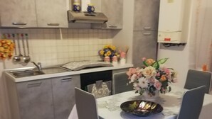 Una cucina moderna con mobili grigi, piano cottura integrato e lavello. C'è un tavolo da pranzo con sedie e un vaso di fiori.