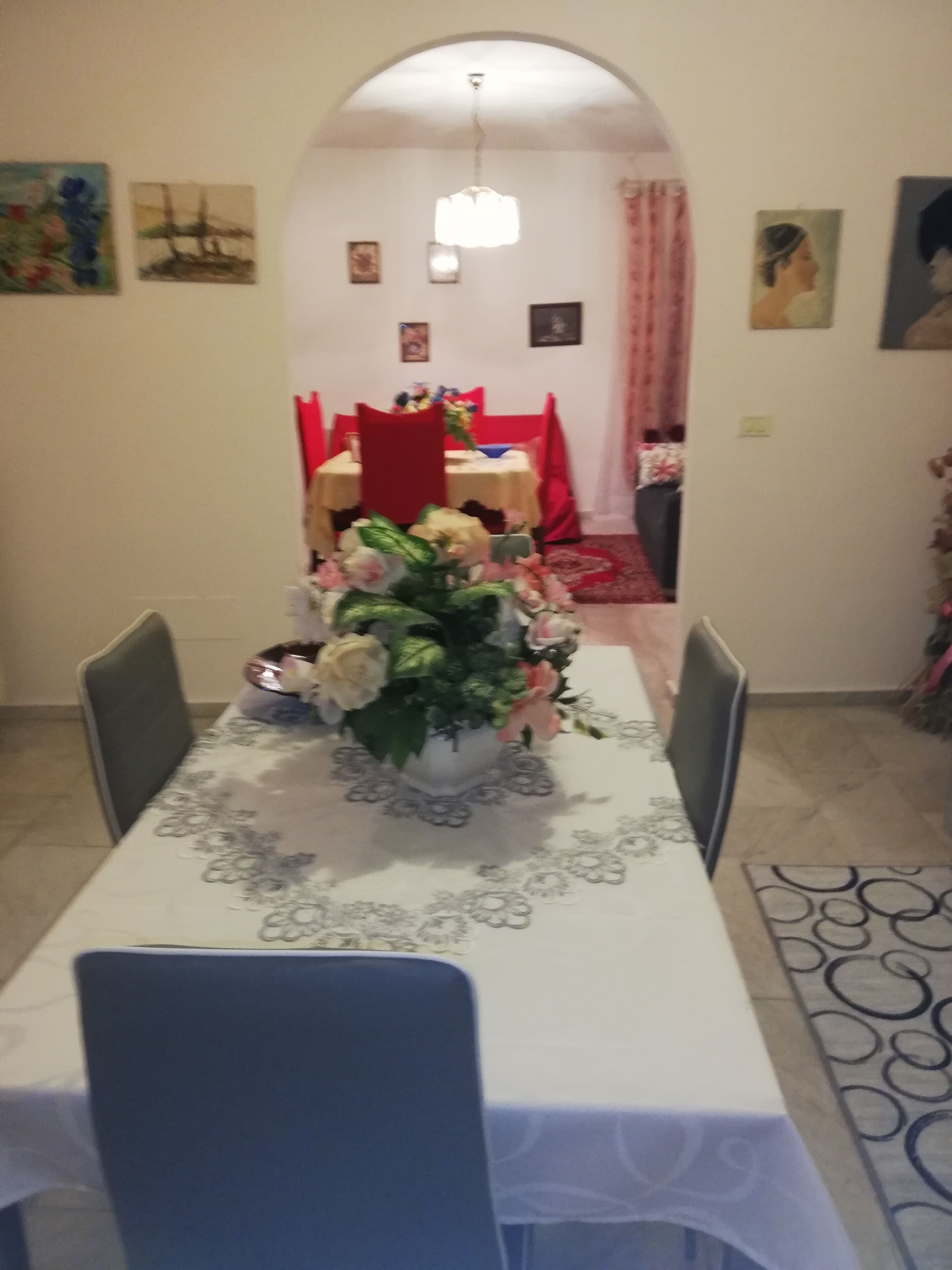 Ein Essbereich mit einem Tisch für vier Personen, einem Blumenstrauß und einem roten Stuhl.