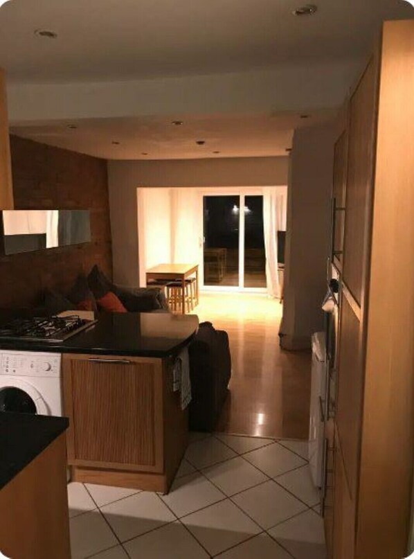 A modern kitchen with a central island, a dining area with a table and chairs, and a sliding glass door leading to an outdoor space.