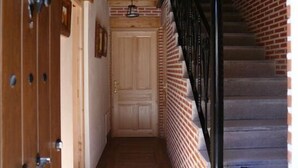 A narrow hallway with wooden doors, a brick wall, and a staircase with black railings. - El Abad rural apartment for 2 people (Vega de Santa María)