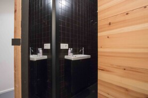 A bathroom with black tiled walls and wooden paneling. - Gorbeia | The Rentals Collection (San Sebastián)