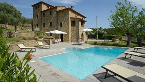 A stone building with a swimming pool, outdoor seating, and a garden. - Torre La Ripa 8, Emma Villas (Cortona)