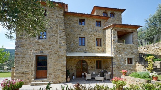 A stone building with a covered patio, outdoor seating, and potted plants. - Torre La Ripa 8, Emma Villas (Cortona)
