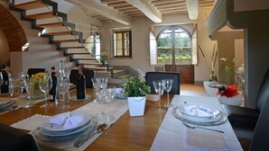 A dining area with a wooden staircase, a table set for a meal, and a view of the outdoors. - Torre La Ripa 8, Emma Villas (Cortona)