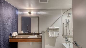 A modern bathroom with a wooden vanity, a large mirror, a shower with a glass door, and a towel rack.