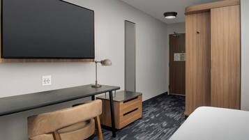 A modern hotel room with a desk, chair, wardrobe, and a bed.