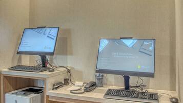 Two computer workstations with monitors, keyboards, and mice, a printer, and a telephone on a desk.