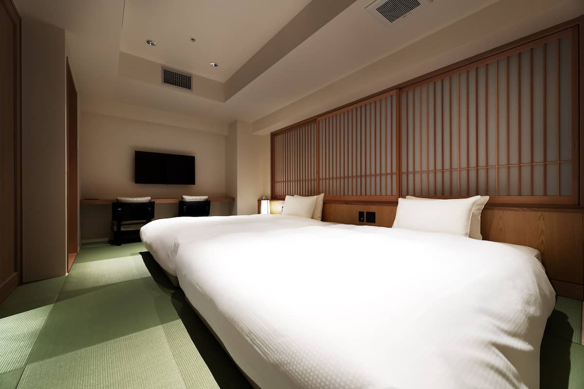 A hotel room with a large bed, a TV mounted on the wall, and a traditional wooden partition.